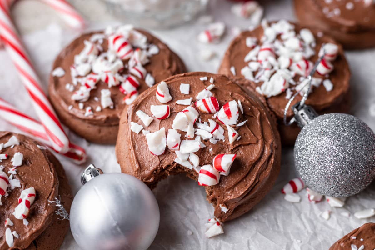 A frosted chocolate peppermint cookies with a bite missing. 