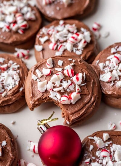 Overlapping stack of frosted chocolate peppermint cookies next to a red ornament.