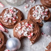 Chocolate frosted peppermint cookies surrounded by candy canes and ornaments.