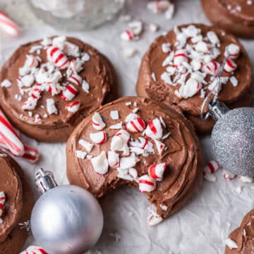 Chocolate frosted peppermint cookies surrounded by candy canes and ornaments.