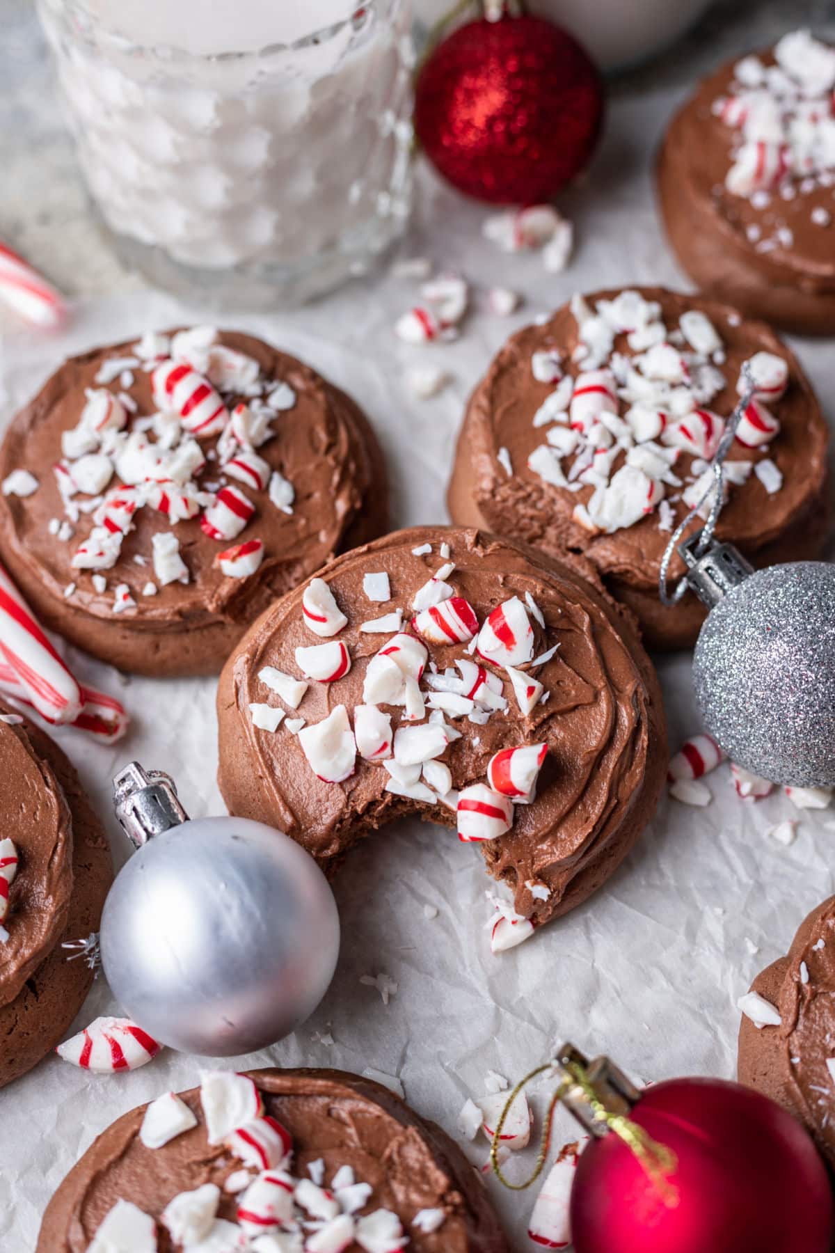 Chocolate frosted peppermint cookies surrounded by candy canes and ornaments.