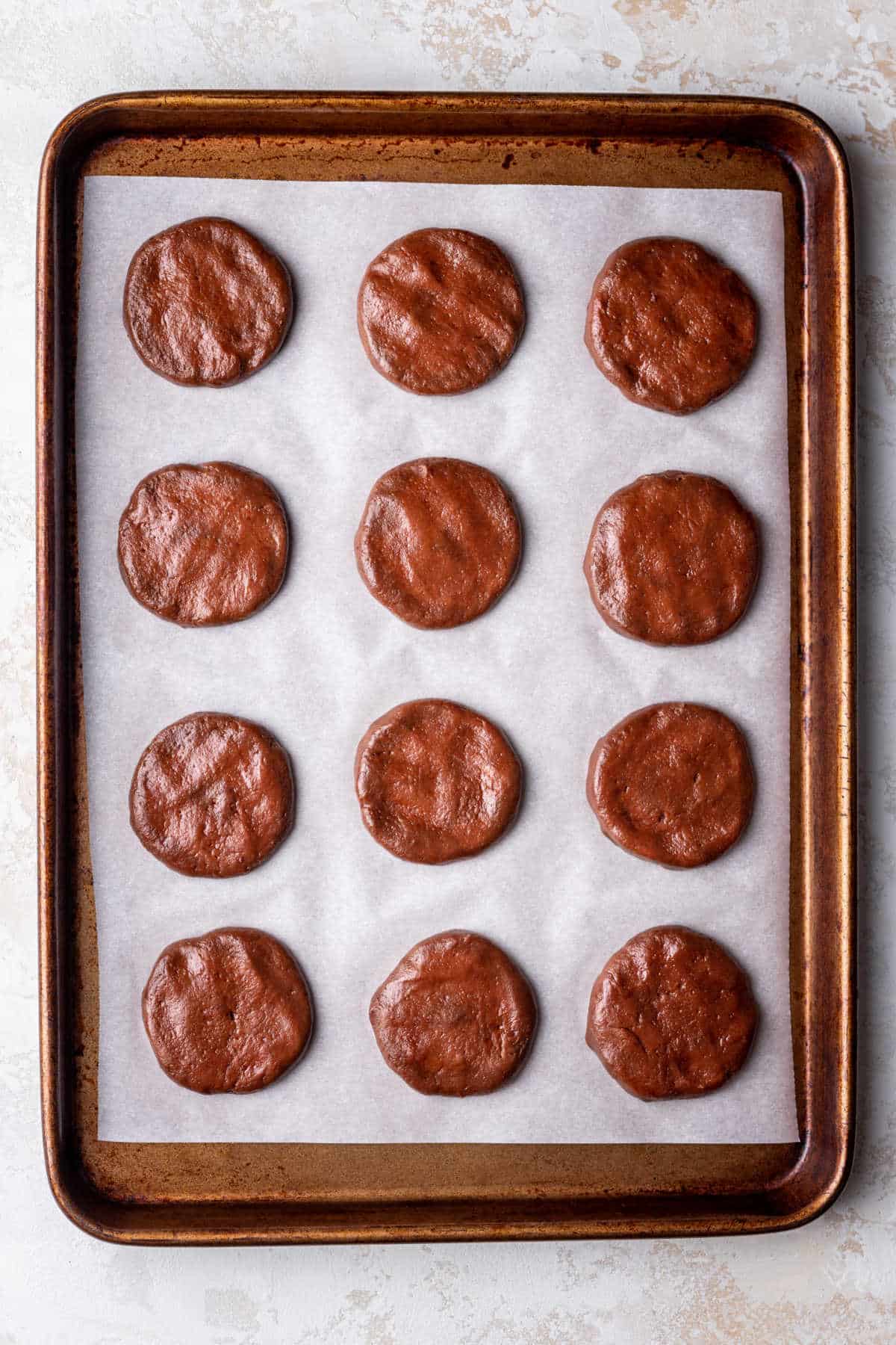 Flattened dough balls on a cookie sheet. 