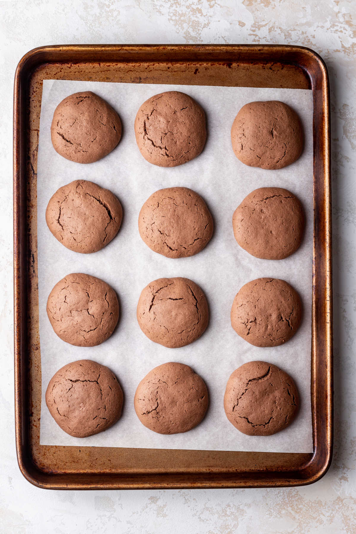 A dozen baked chocolate cookies on a baking sheet. 