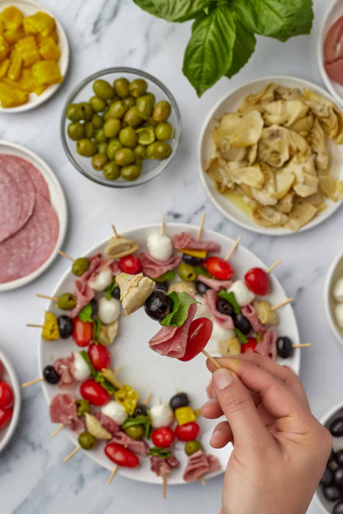 A hand holding a skewer with charcuterie ingredients. 