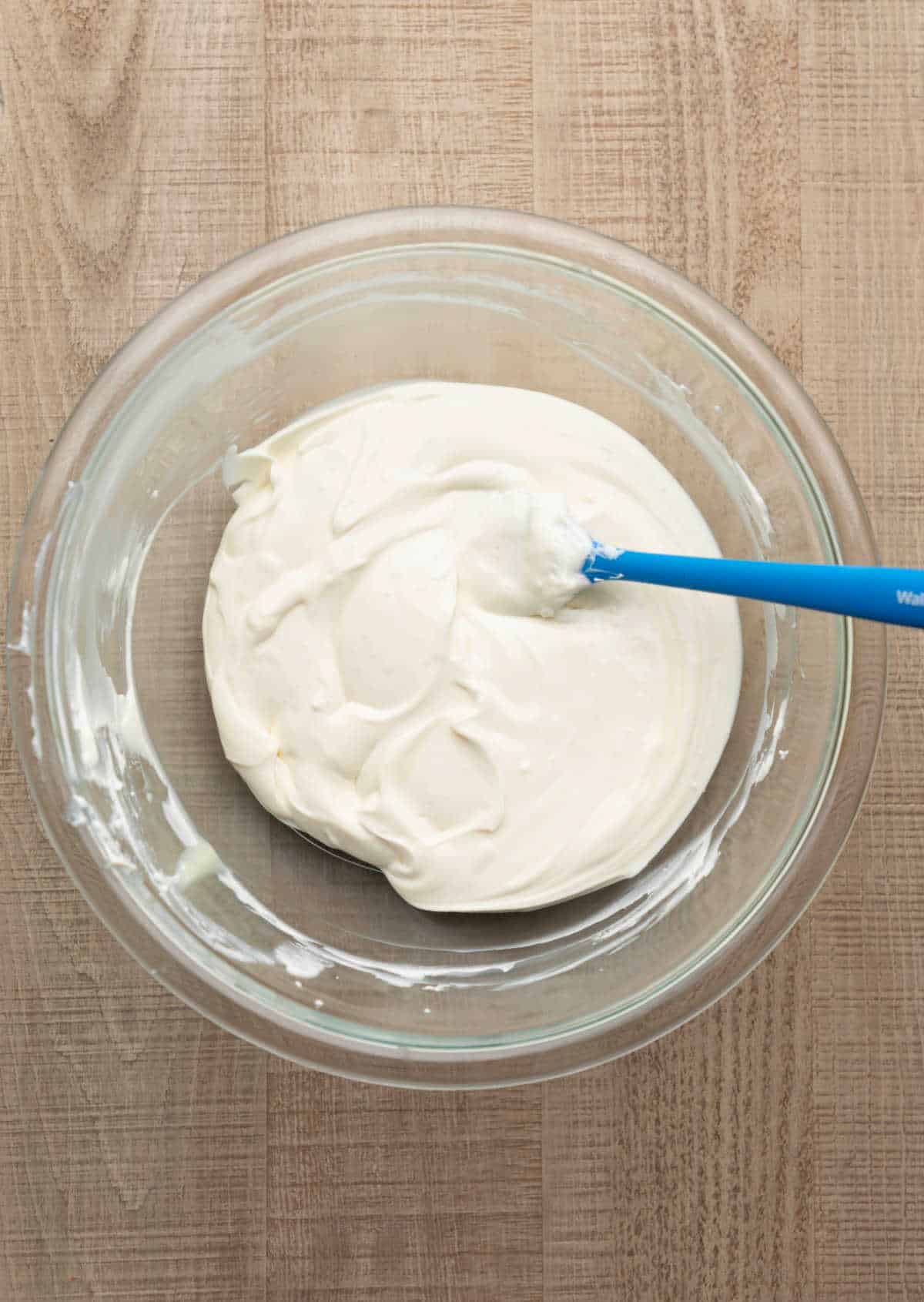 Cream cheese greek yogurt and sweetened condensed milk mixed in a mixing bowl.  