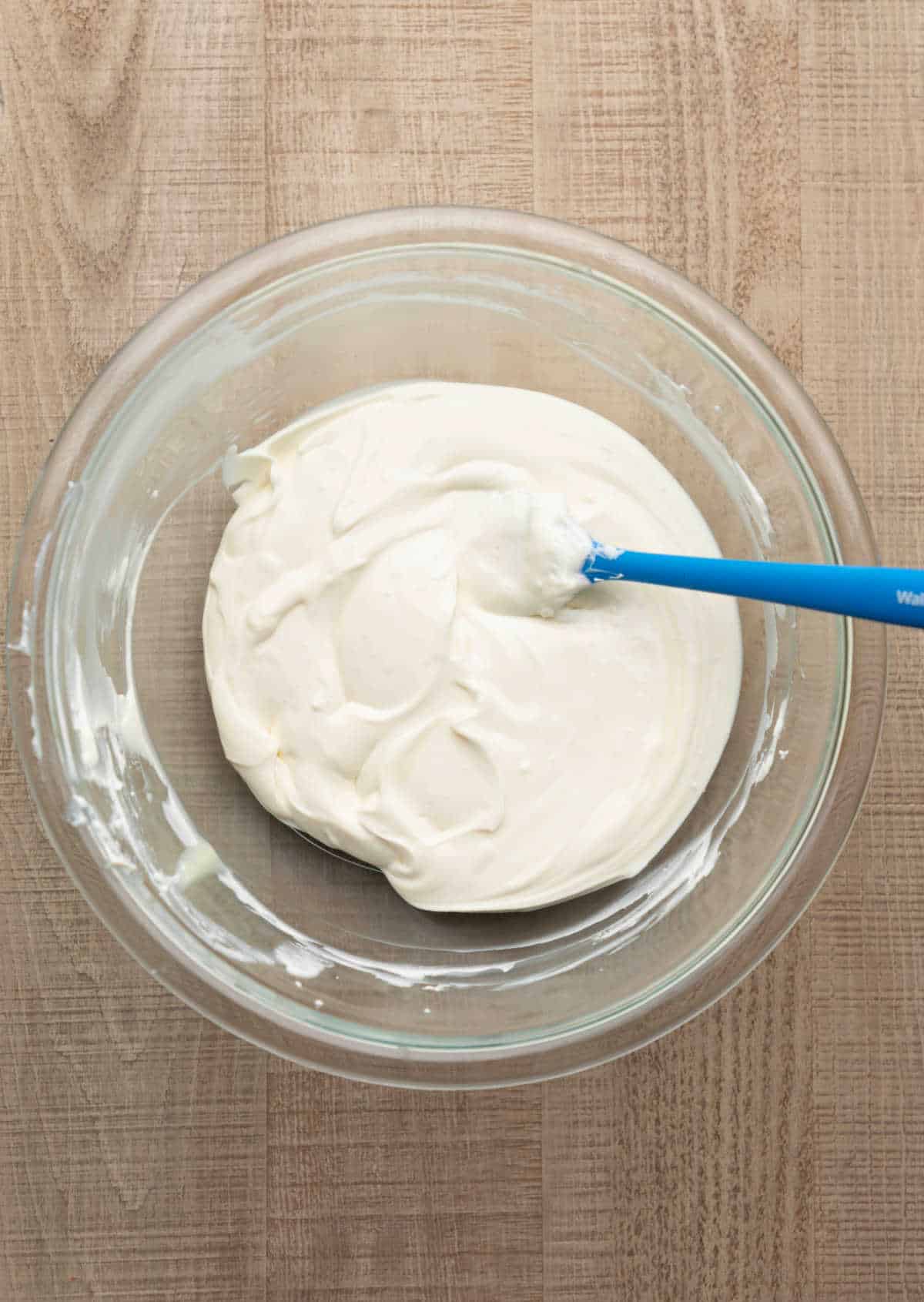 Cream cheese greek yogurt and sweetened condensed milk mixed in a mixing bowl.