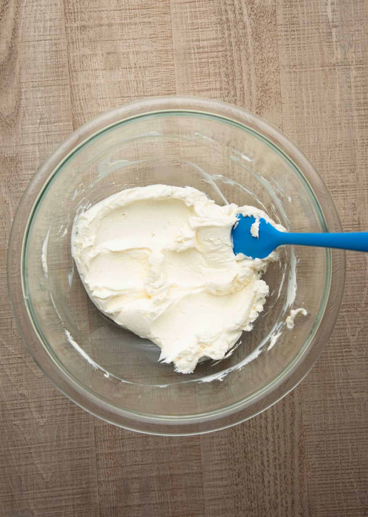 Beaten cream cheese in a glass mixing bowl.