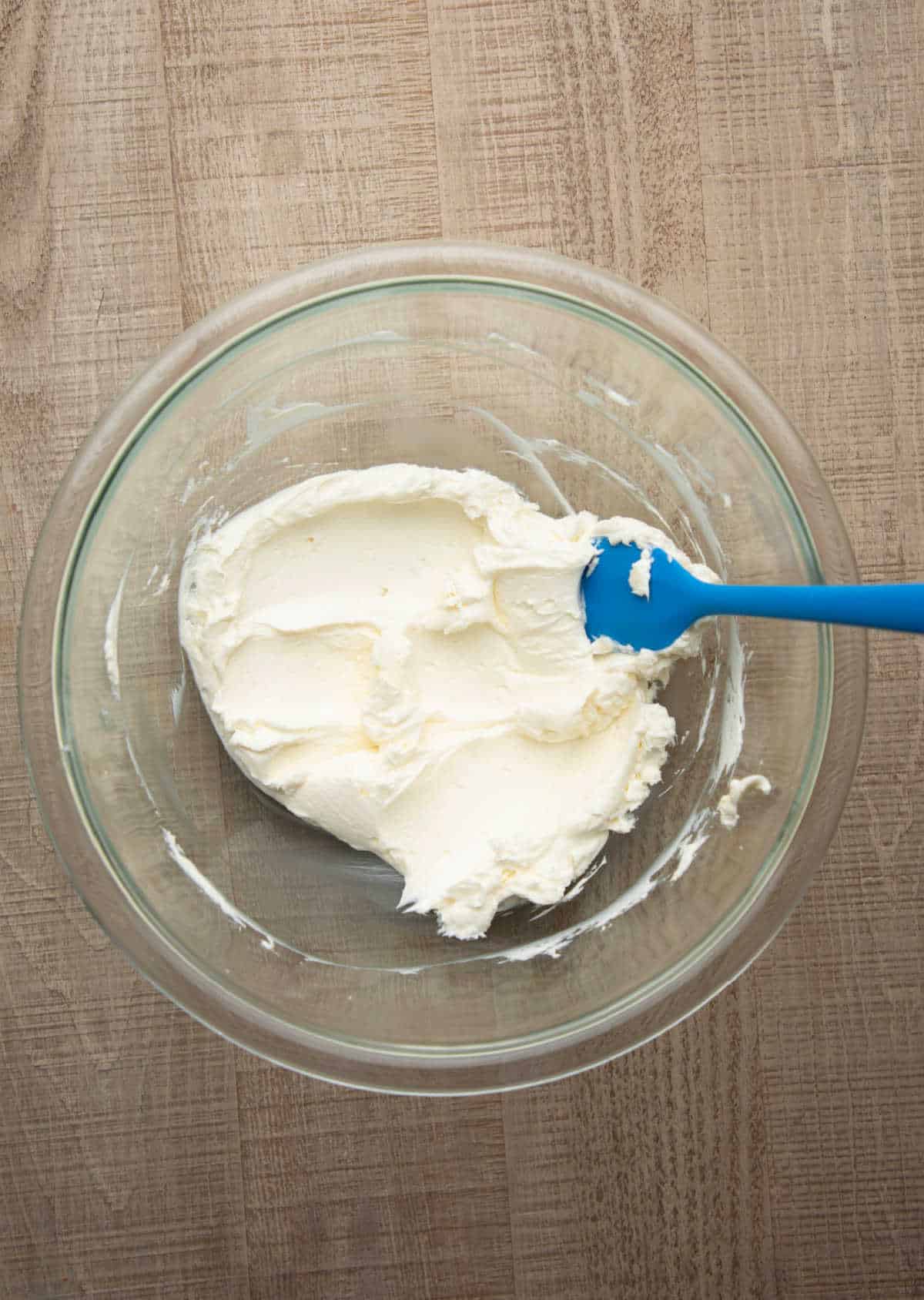 Beaten cream cheese in a glass mixing bowl. 