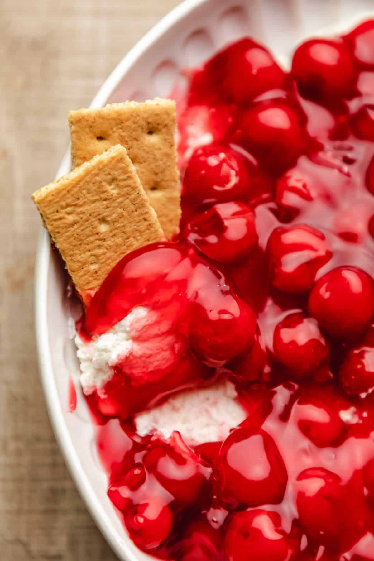 Cherry Cheesecake Dip Two graham cracker pieces upright with cherry cheesecake dip on them.