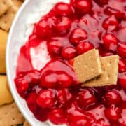 Two graham cracker pieces scooping up cherry cheesecake dip.