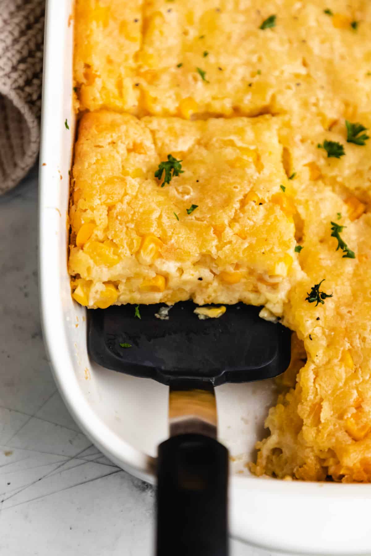 A spatula removing a piece from a corn casserole.