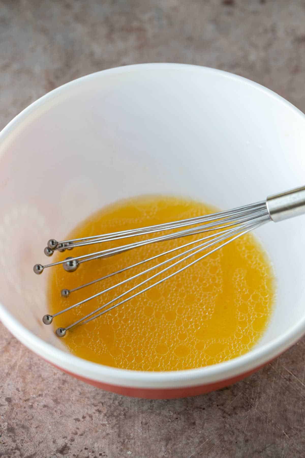 Oil and orange juice in a mixing bowl. 