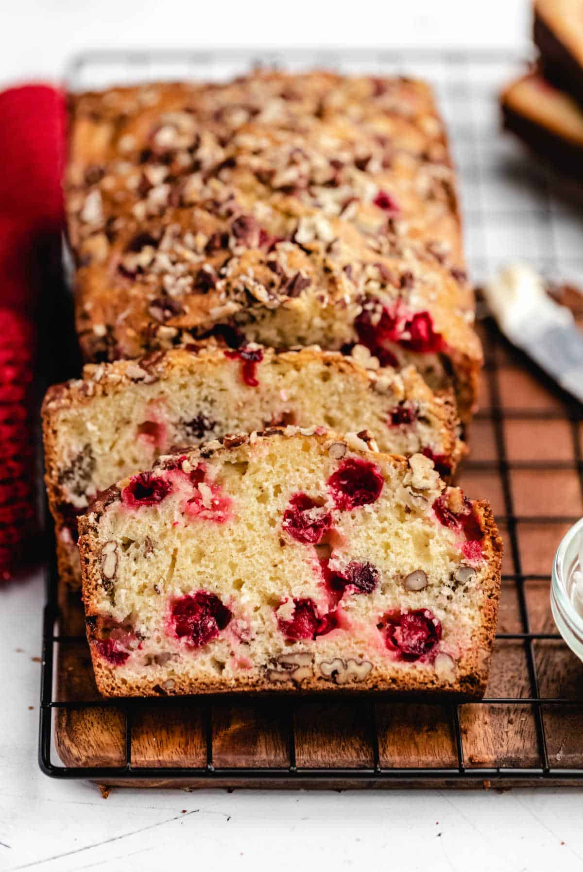A loaf of cranberry nut bread on a wire cooling rack. 