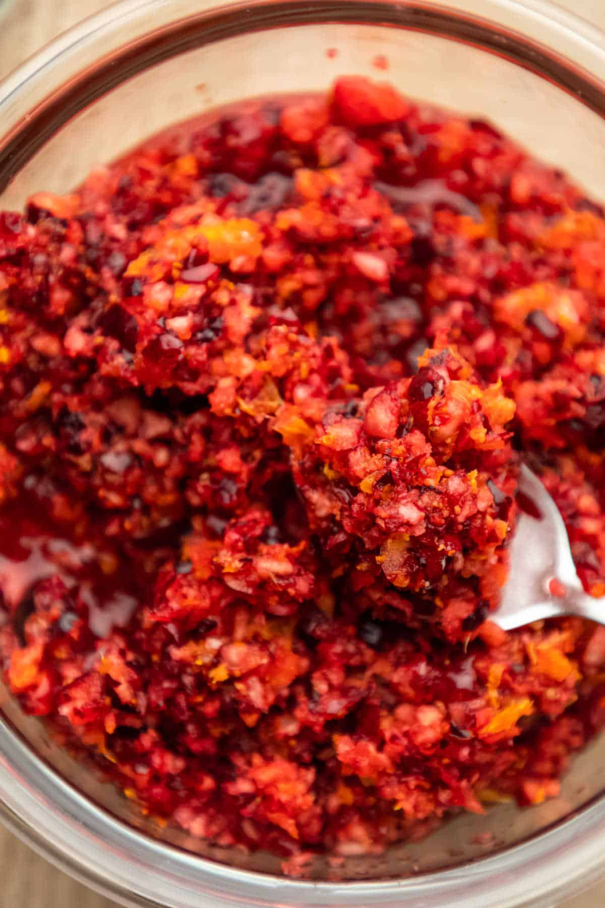 A silver spoon scooping up cranberry orange relish.