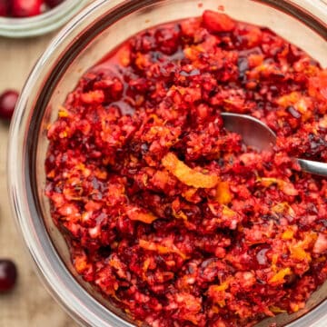 A glass dish of cranberry orange relish with a strip of orange peel on top.