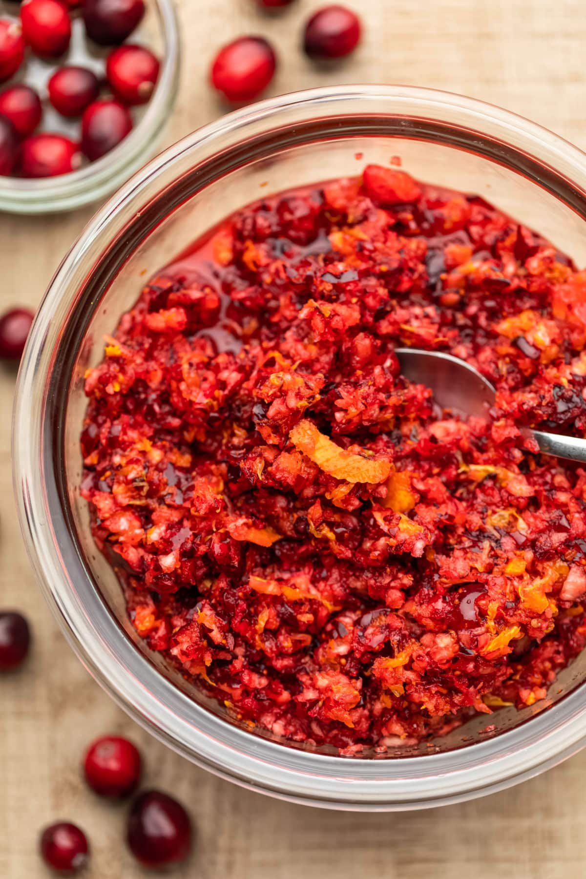 A glass dish of cranberry orange relish with a strip of orange peel on top. 