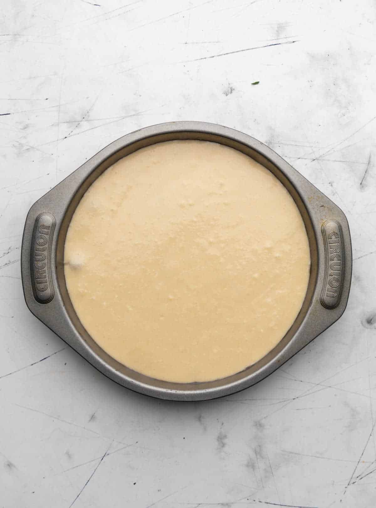 Cake batter over cranberry topping in a cake pan.