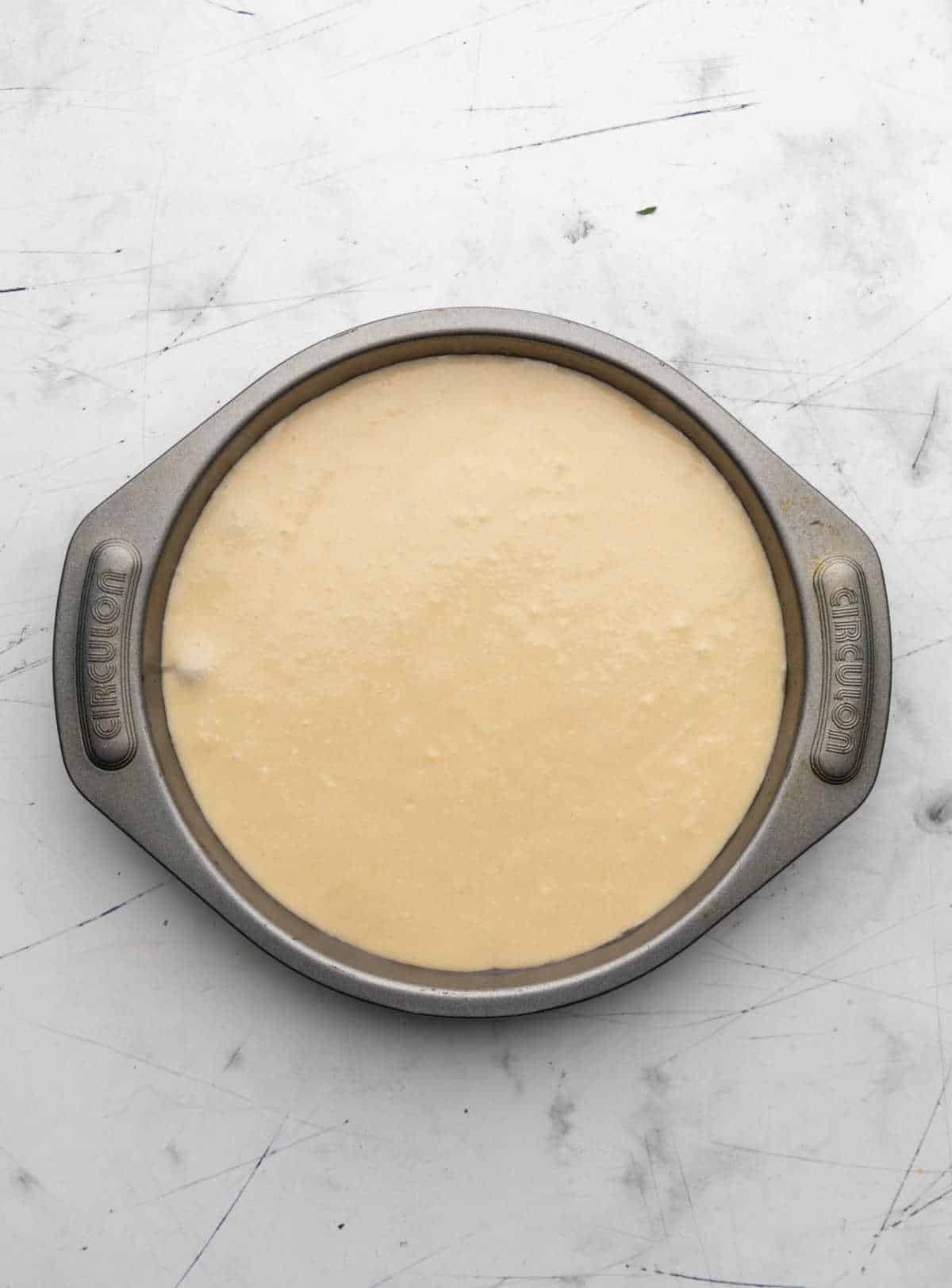 Cake batter over cranberry topping in a cake pan. 