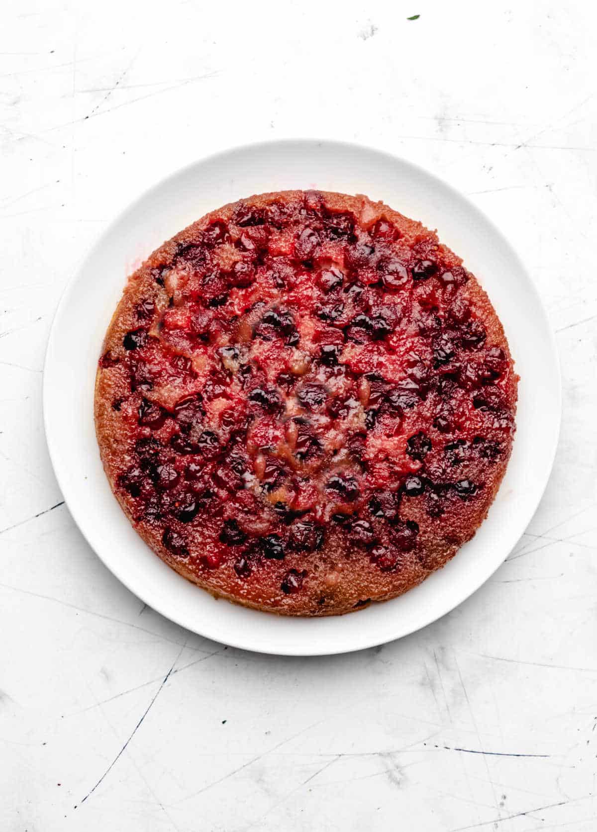 Baked cranberry upside down cake on a white platter.