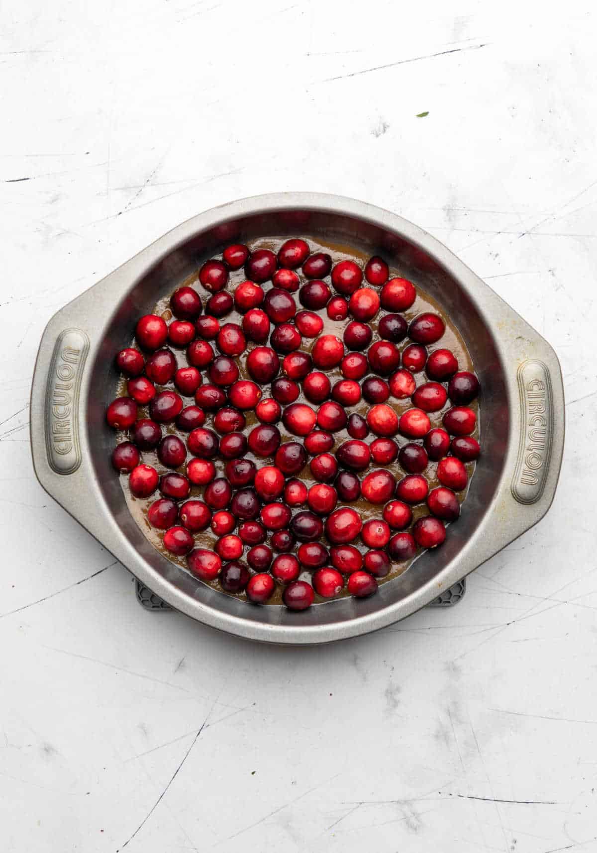 Fresh cranberries over brown sugar topping in a round cake pan.