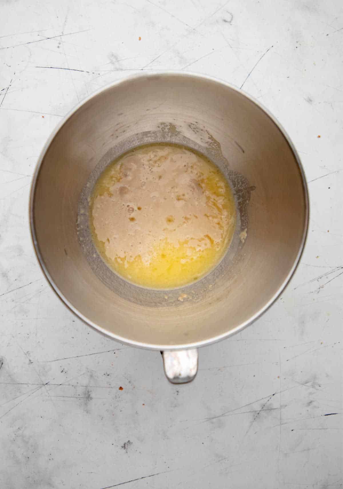 Foamy yeast mixture in a silver mixing bowl. 