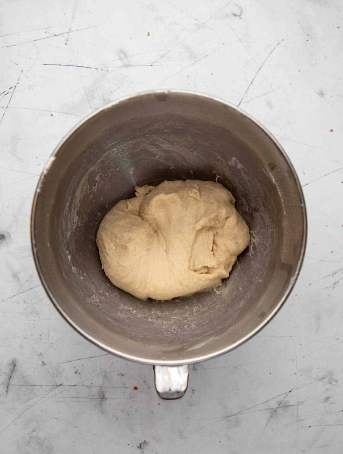 Kneaded crescent roll dough in a silver mixing bowl. 