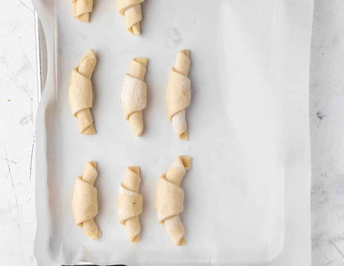 Unbaked crescent rolls on a baking sheet. 