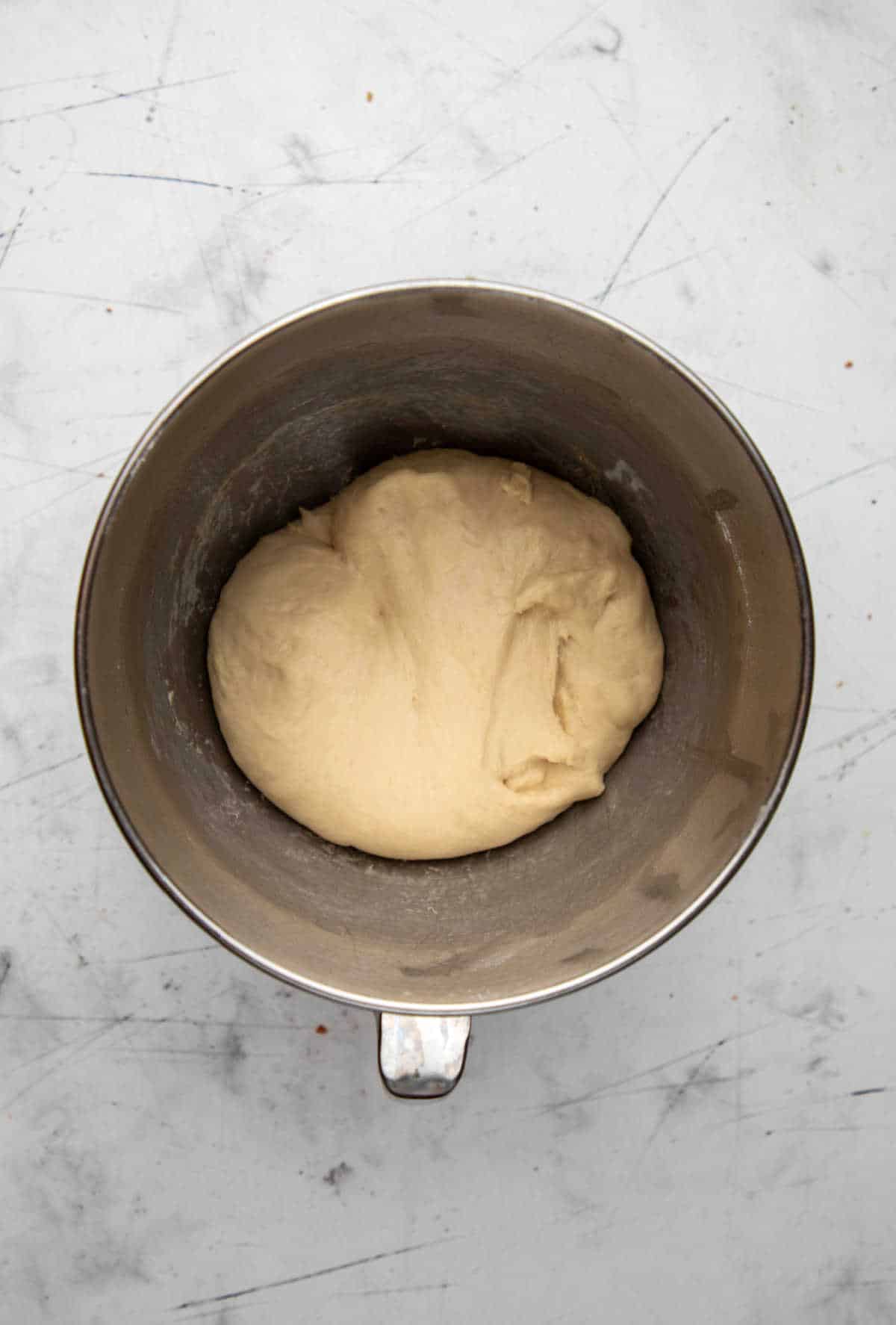 Risen crescent roll dough in a silver mixing bowl. 