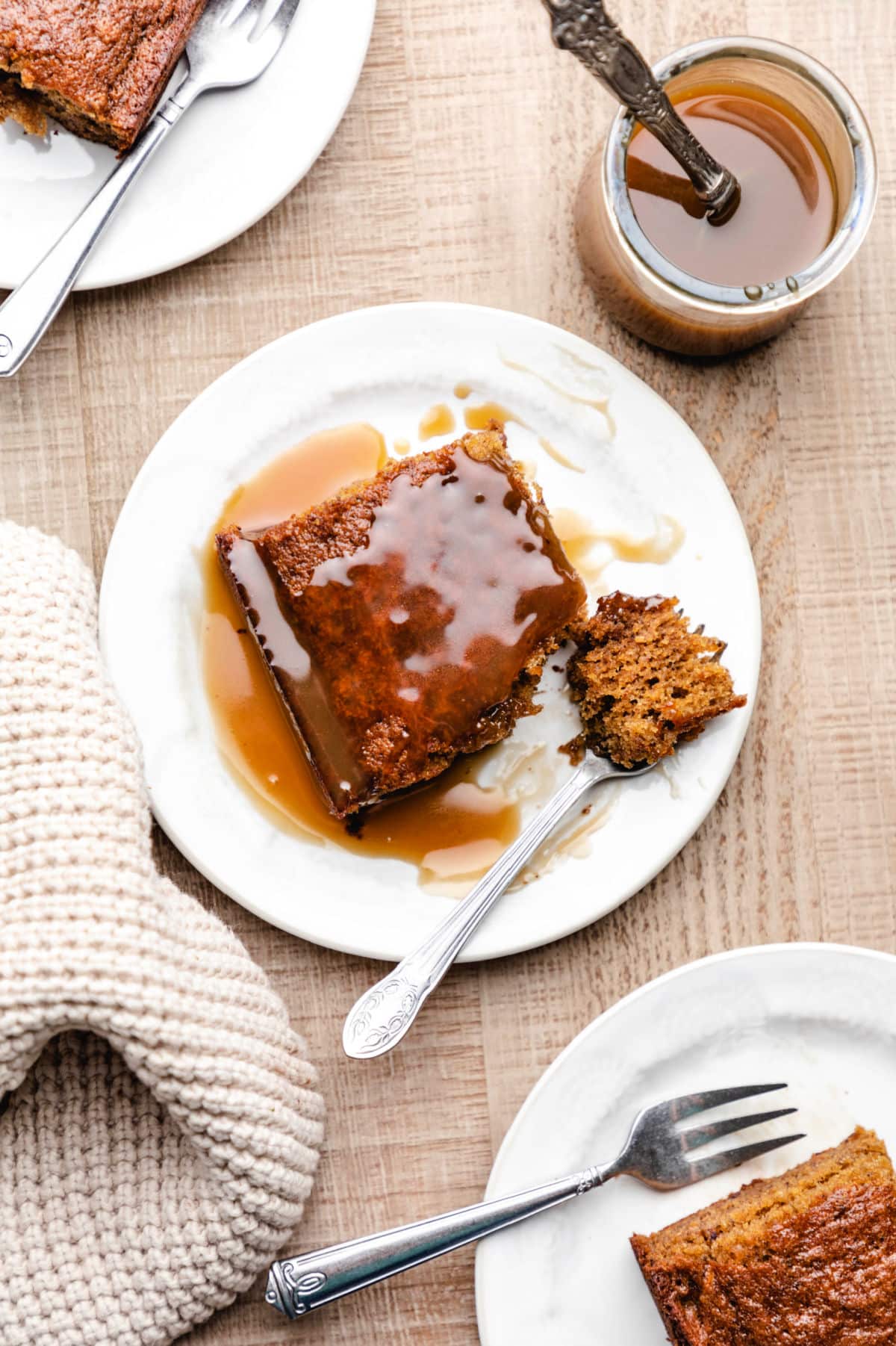 Three plates with slices of sticky toffee pudding cake and forks.