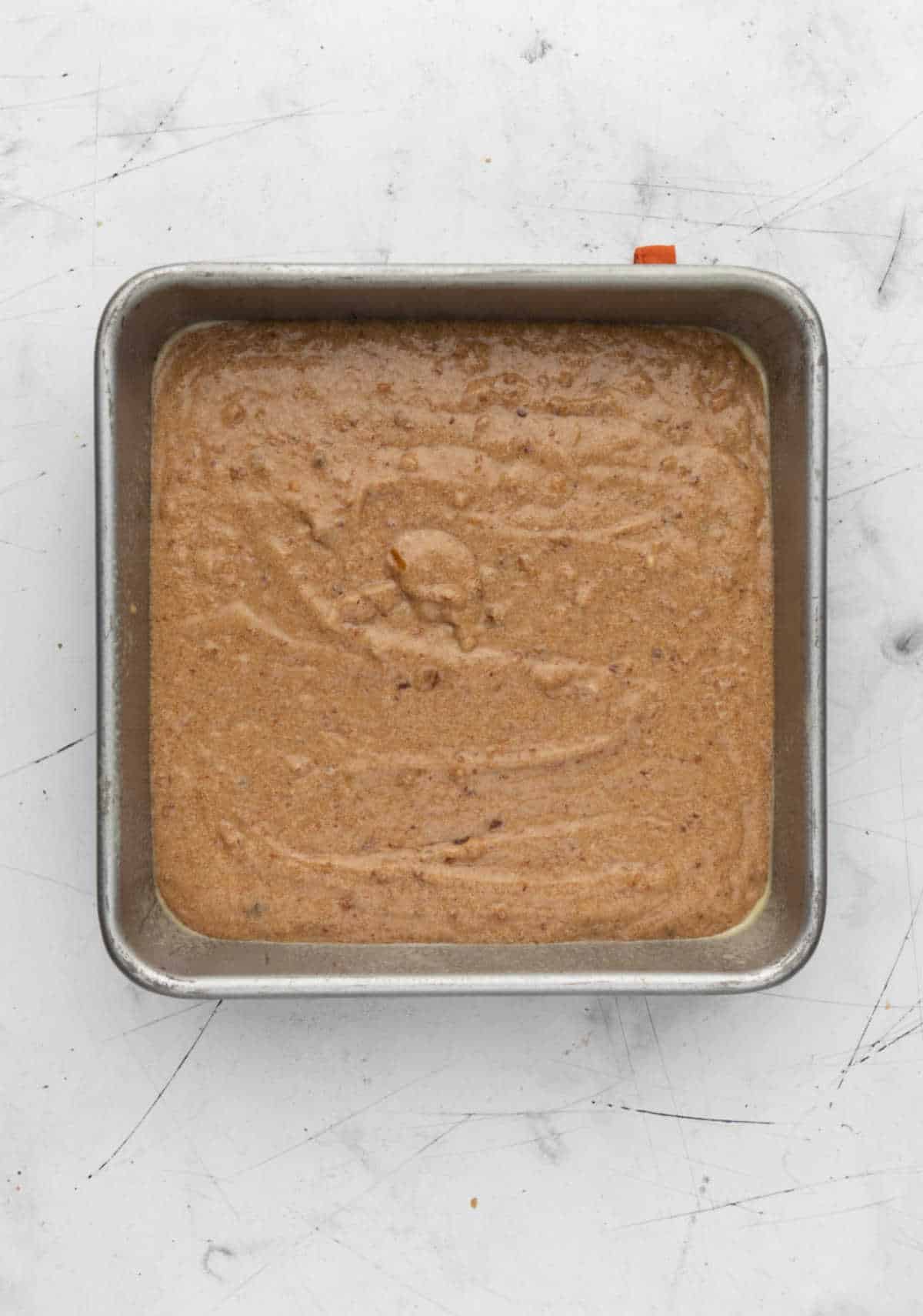 Sticky toffee pudding cake batter in a square cake pan. 