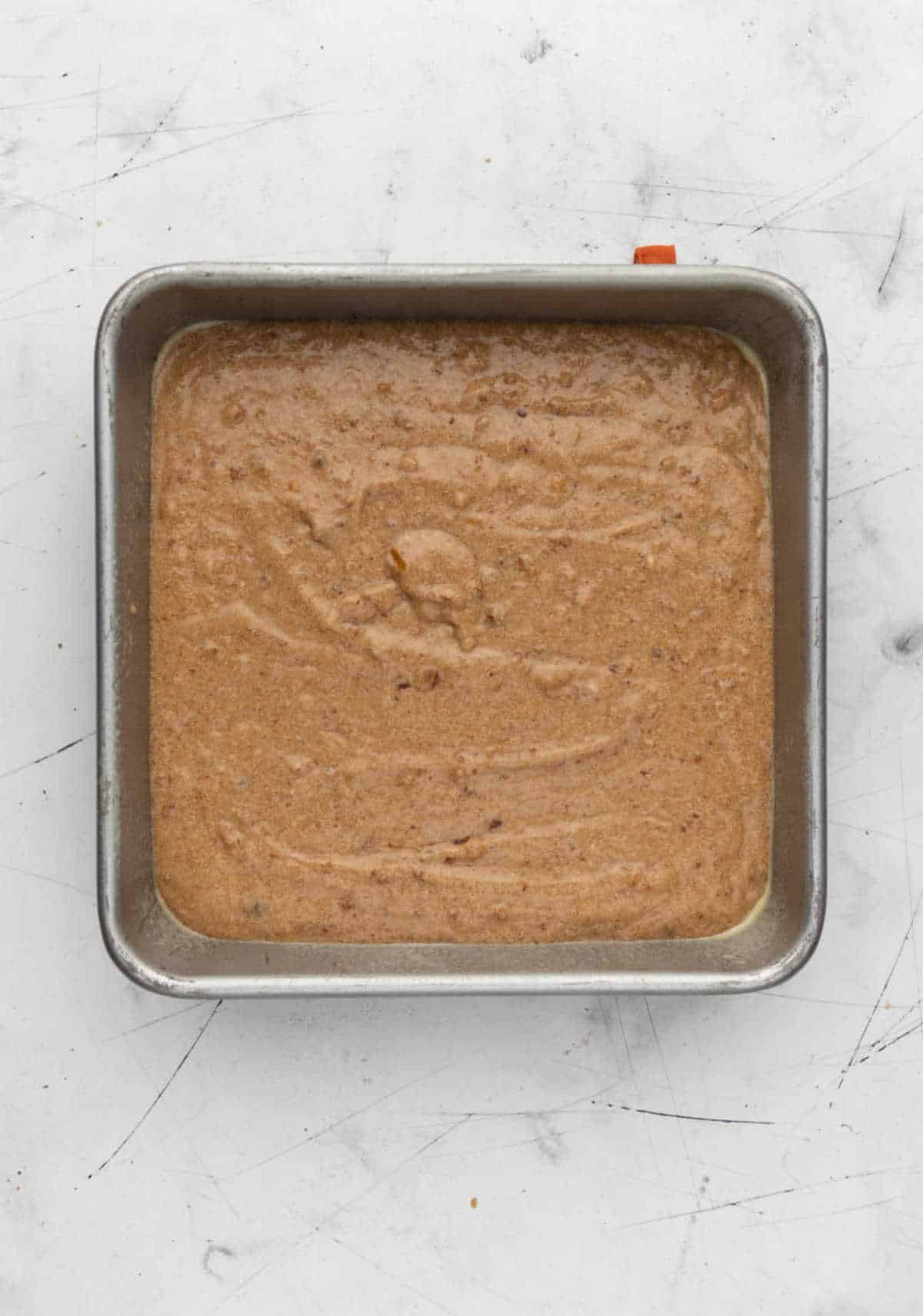 Sticky toffee pudding cake batter in a square cake pan.