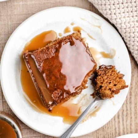 A piece of sticky toffee pudding cake with a bite on a fork.