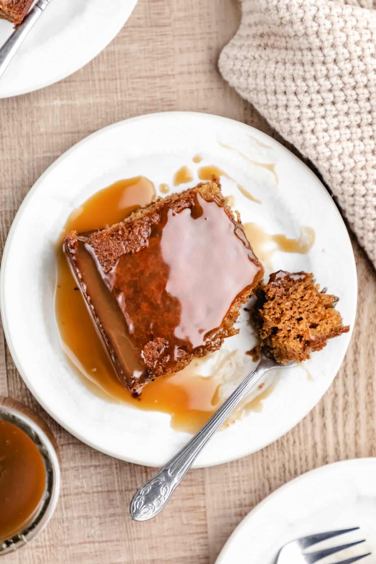 A piece of sticky toffee pudding cake with a bite on a fork. 