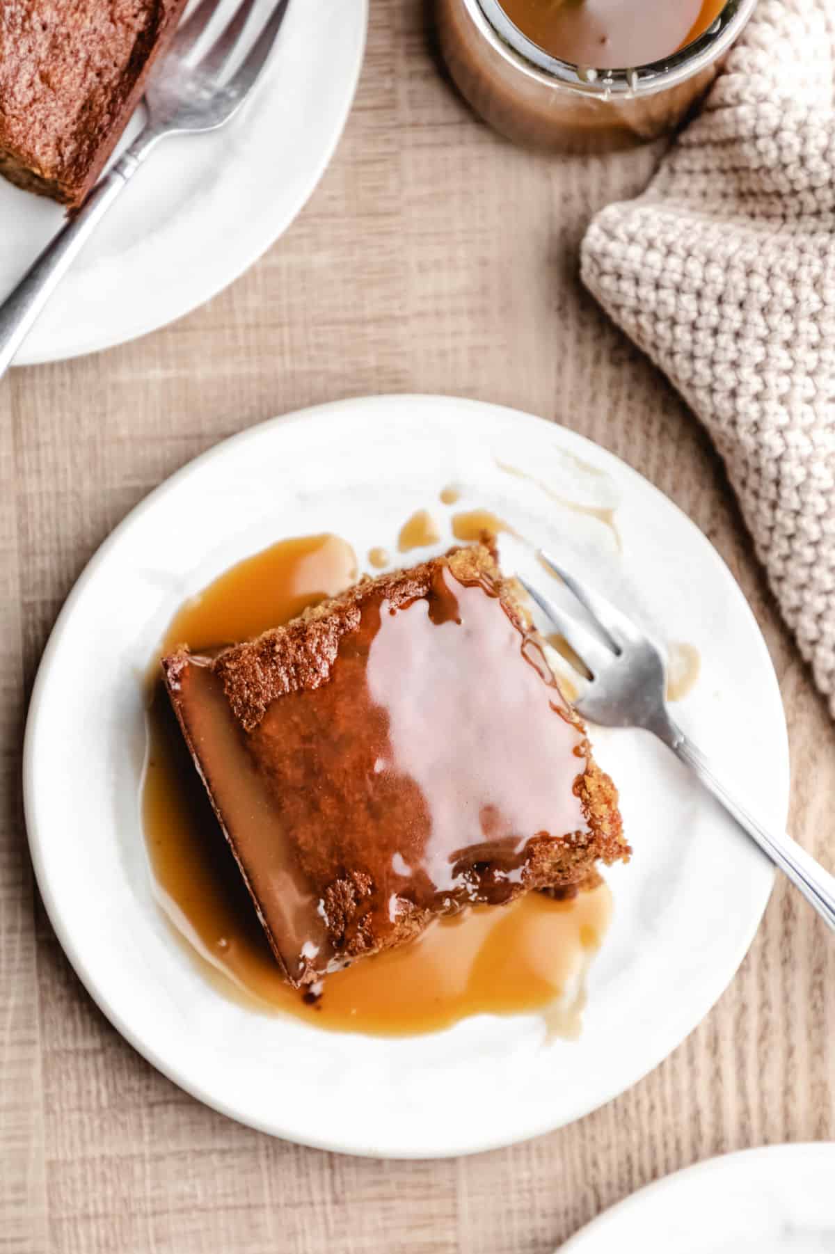 A slice of sticky toffee pudding cake topped with toffee sauce.