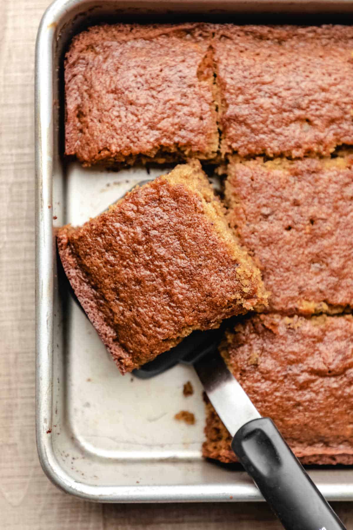 A spatula removing pieces of sticky toffee pudding cake from a pan. 