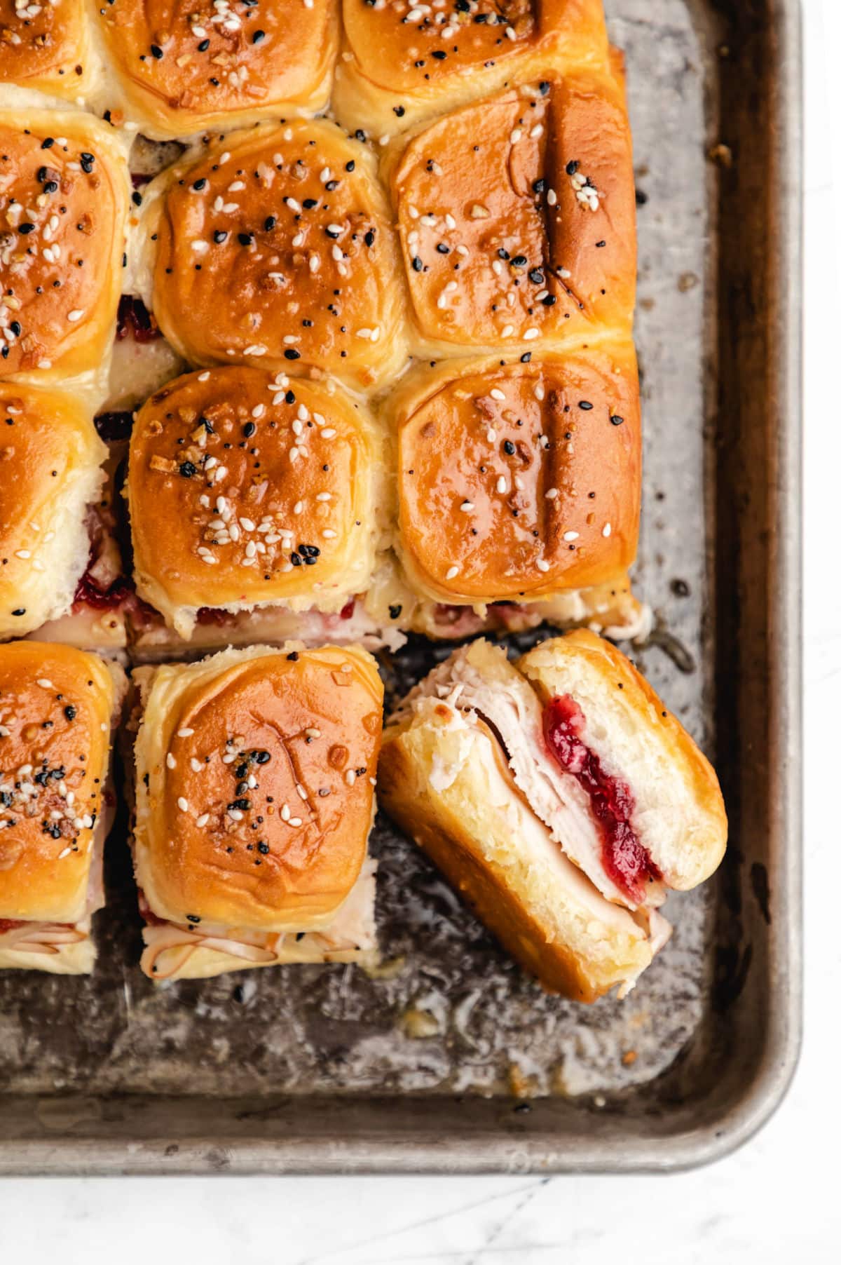 A turkey cranberry slider sideways next to rows of turkey sliders. 