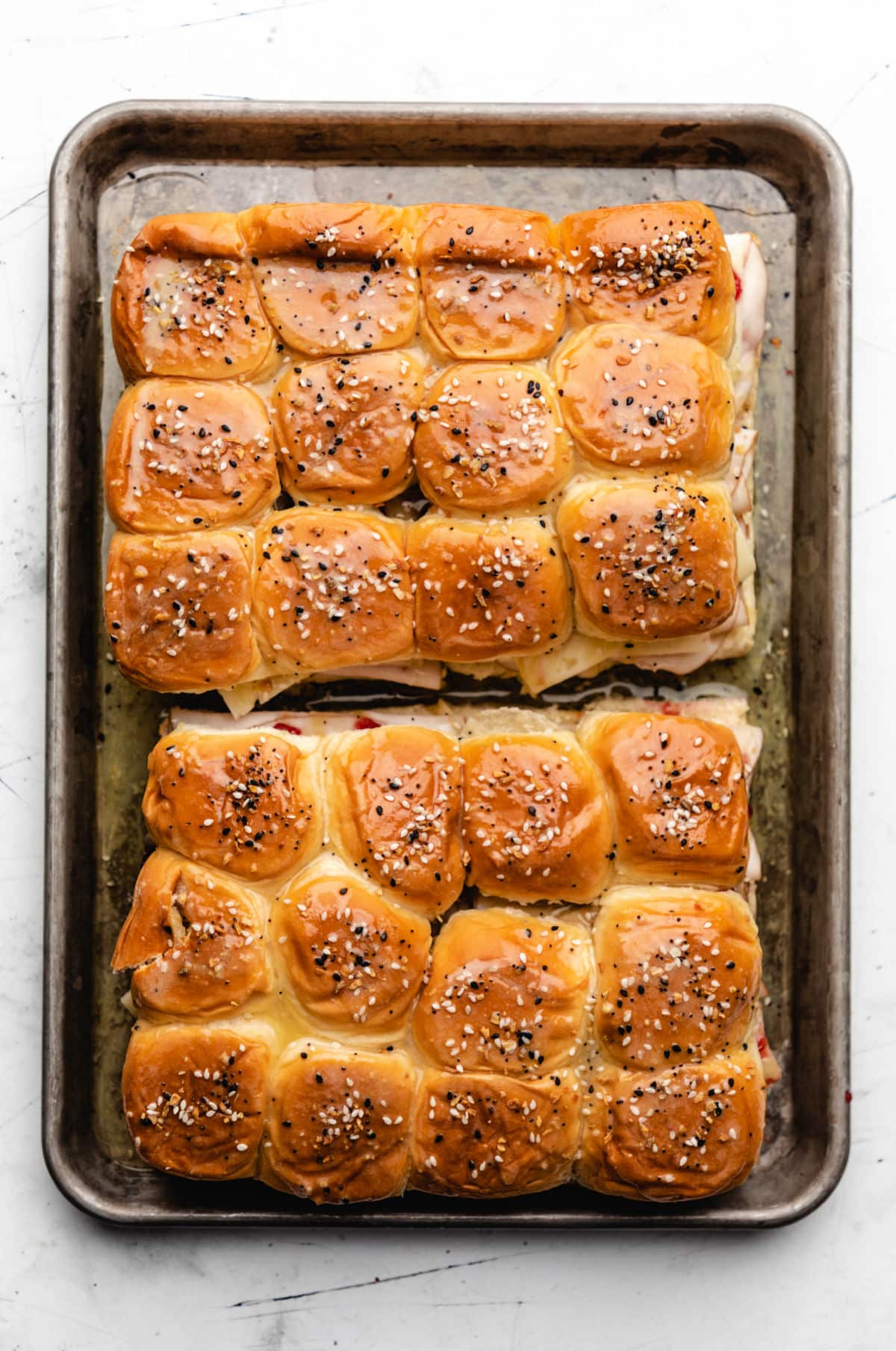 Baked turkey and cranberry sliders on a rimmed baking sheet. 