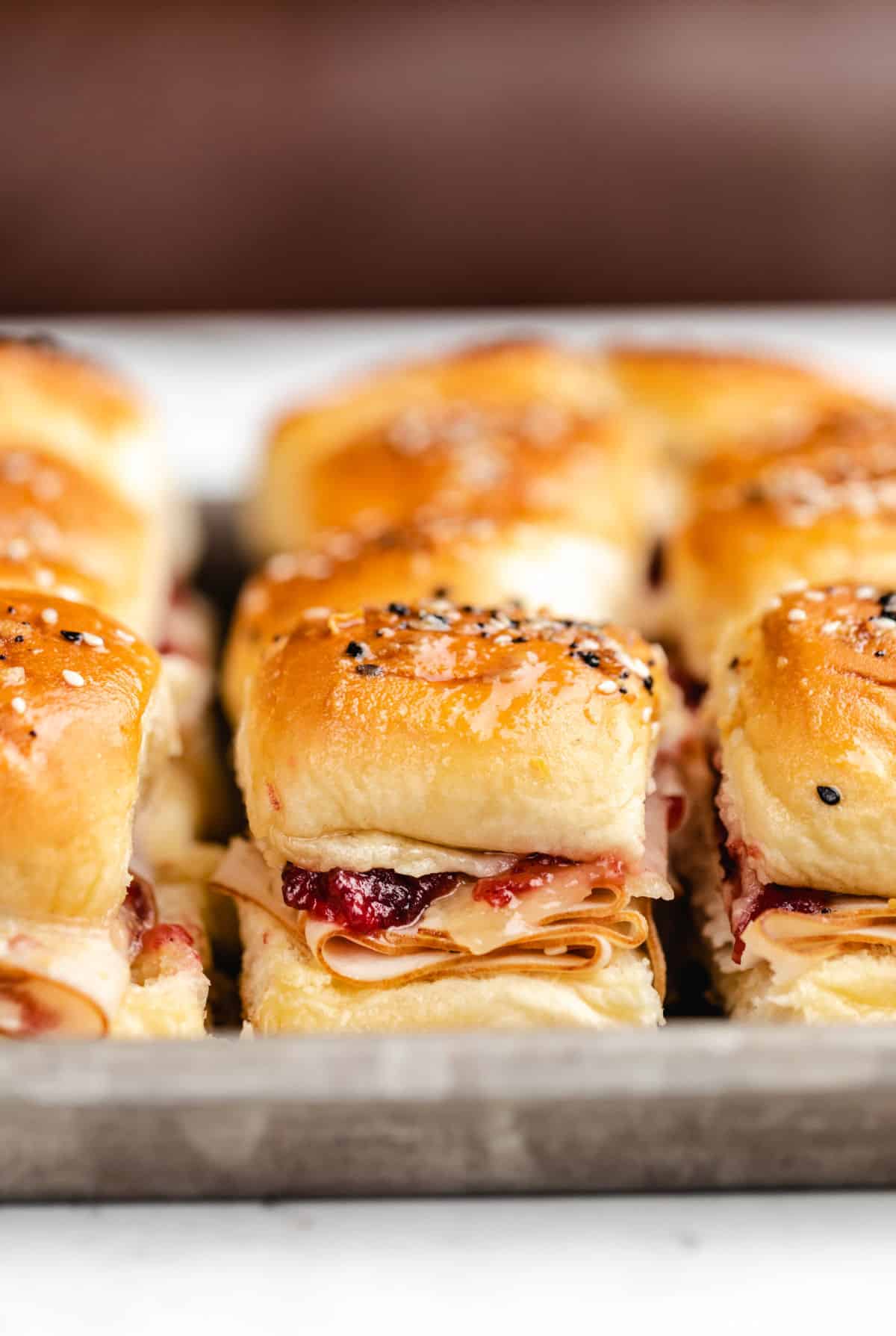 Turkey cranberry sliders on a rimmed baking sheet. 