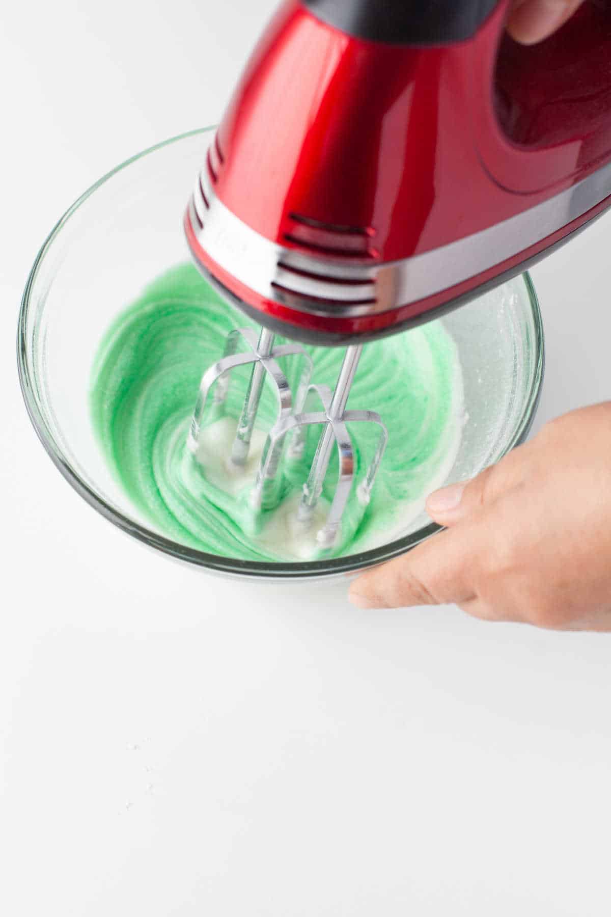 Green food coloring mixing into buttercream frosting. 