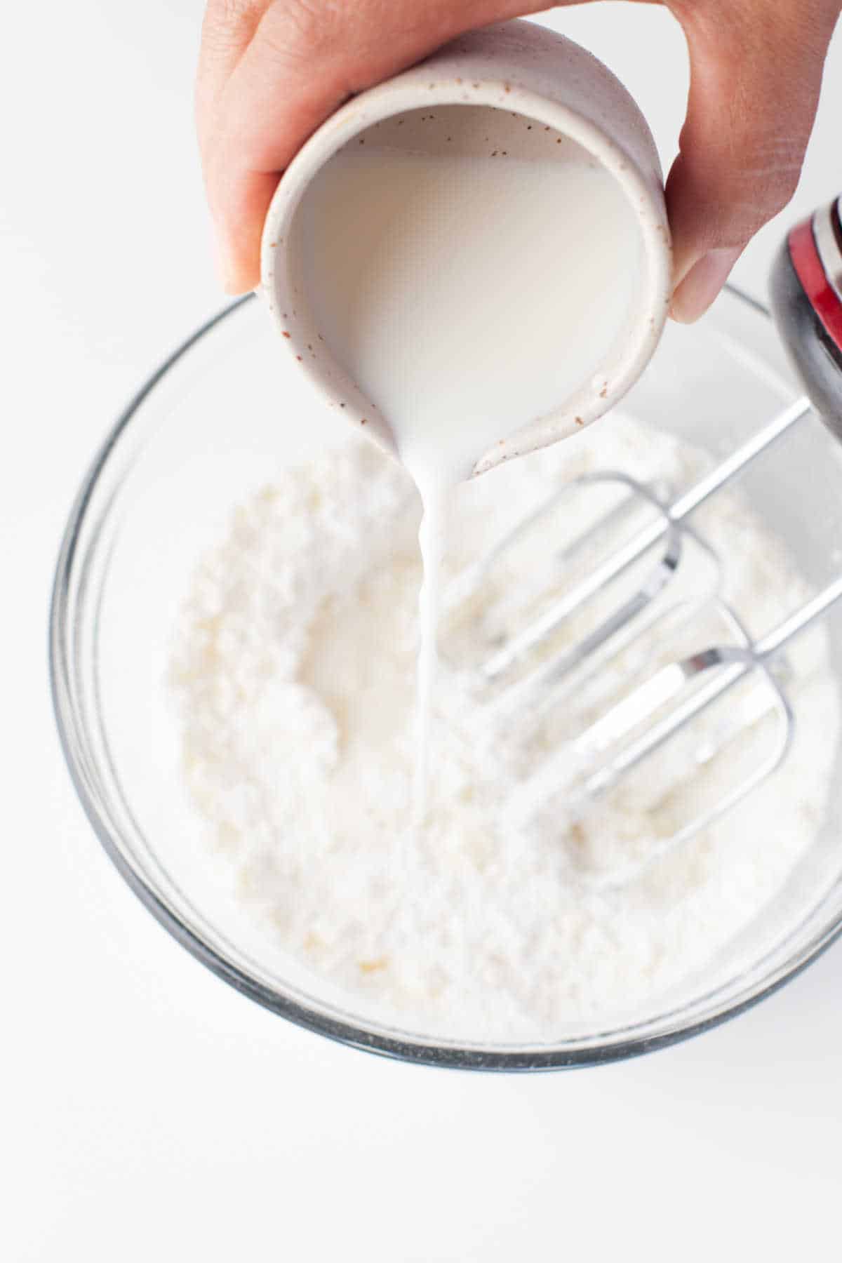 Cream pouring onto powdered sugar in a bowl. 