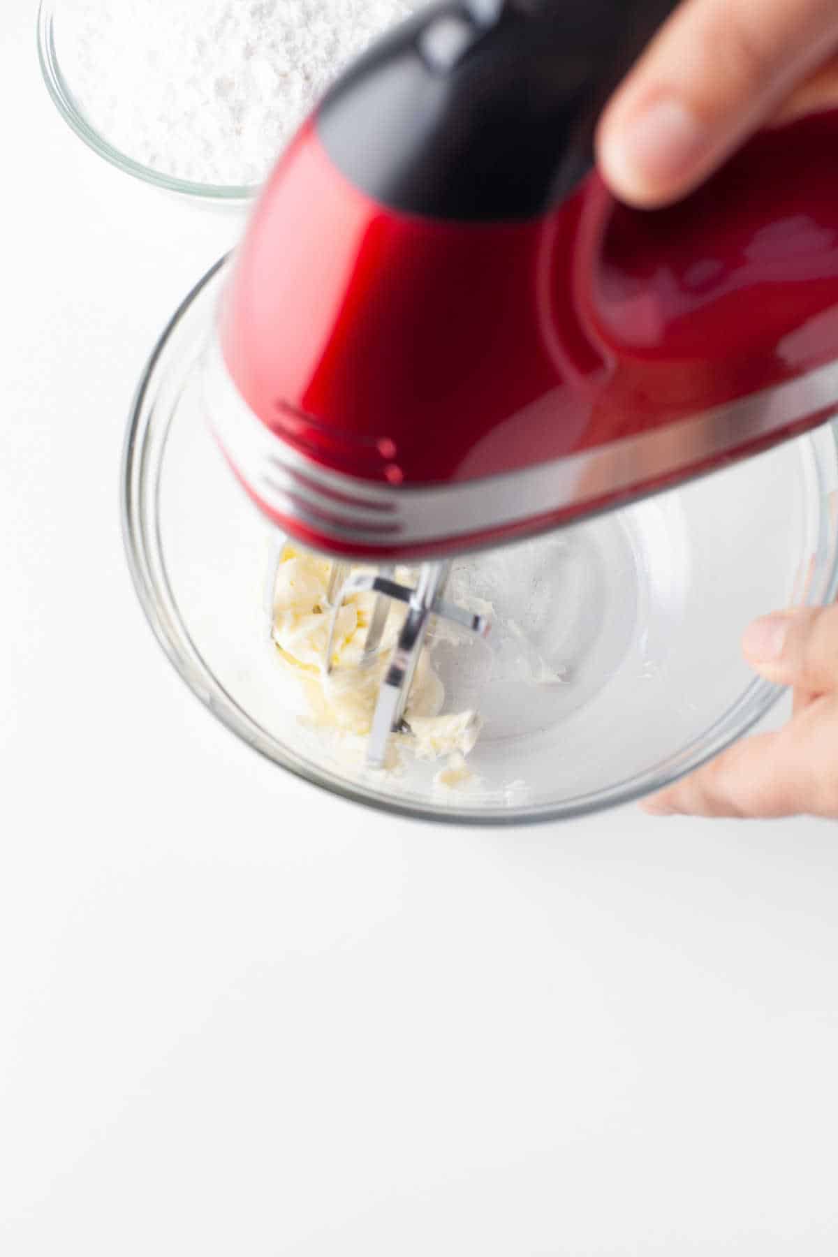 A hand mixer beating butter in a mixing bowl. 