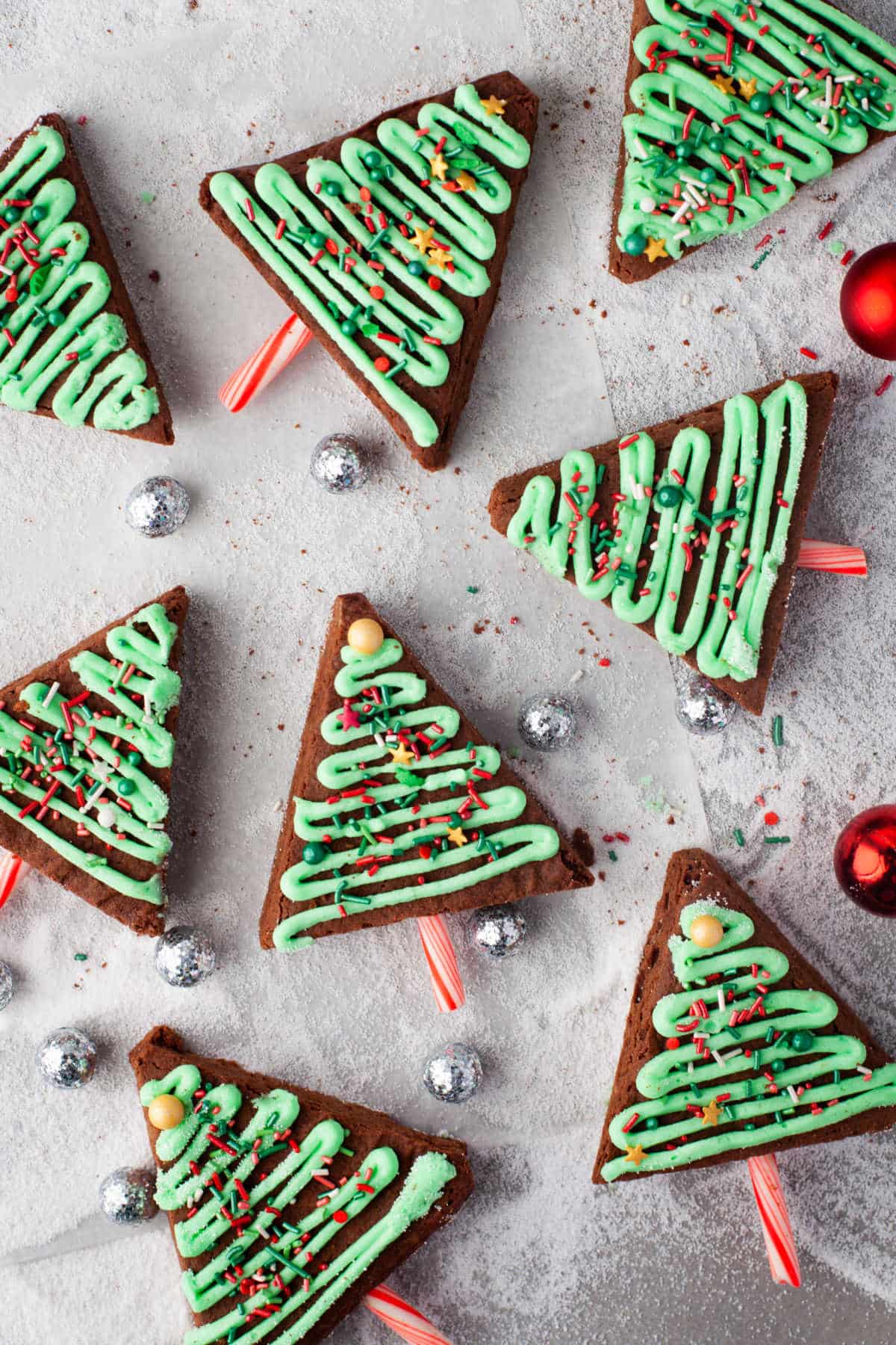 Christmas tree brownies with christmas ornaments around them. 