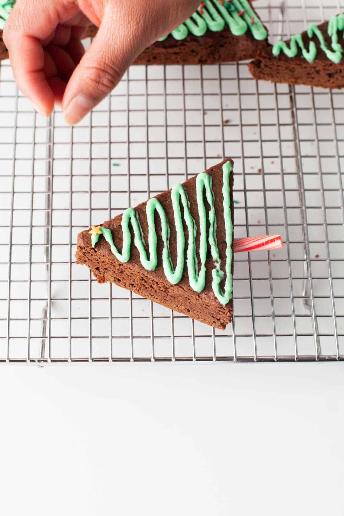 A hand dropping sprinkles onto brownies. 