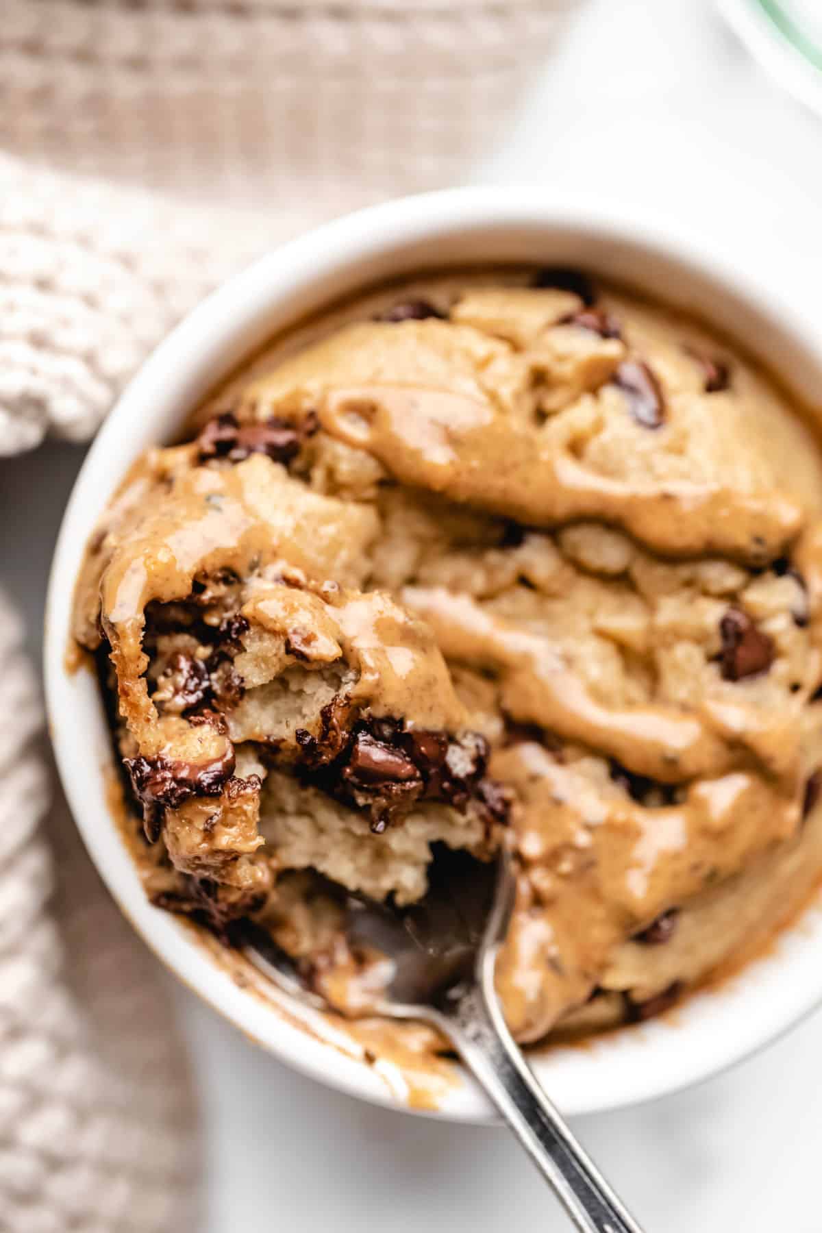 A spoon with a bite of blended baked oats topped with peanut butter.