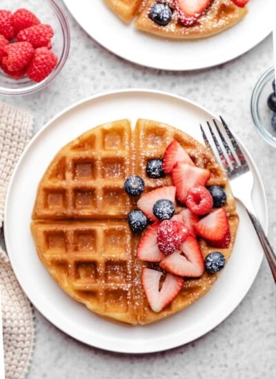 A buttermilk waffle topped with blueberries strawberries and raspberries.