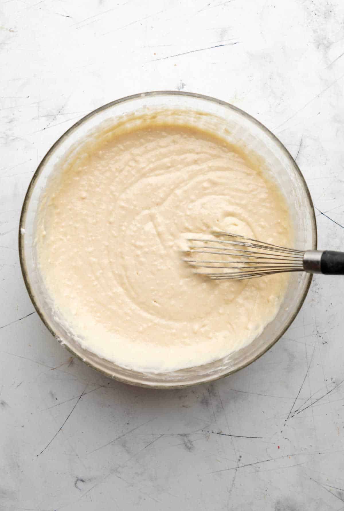 Buttermilk waffle batter in a glass mixing bowl. 