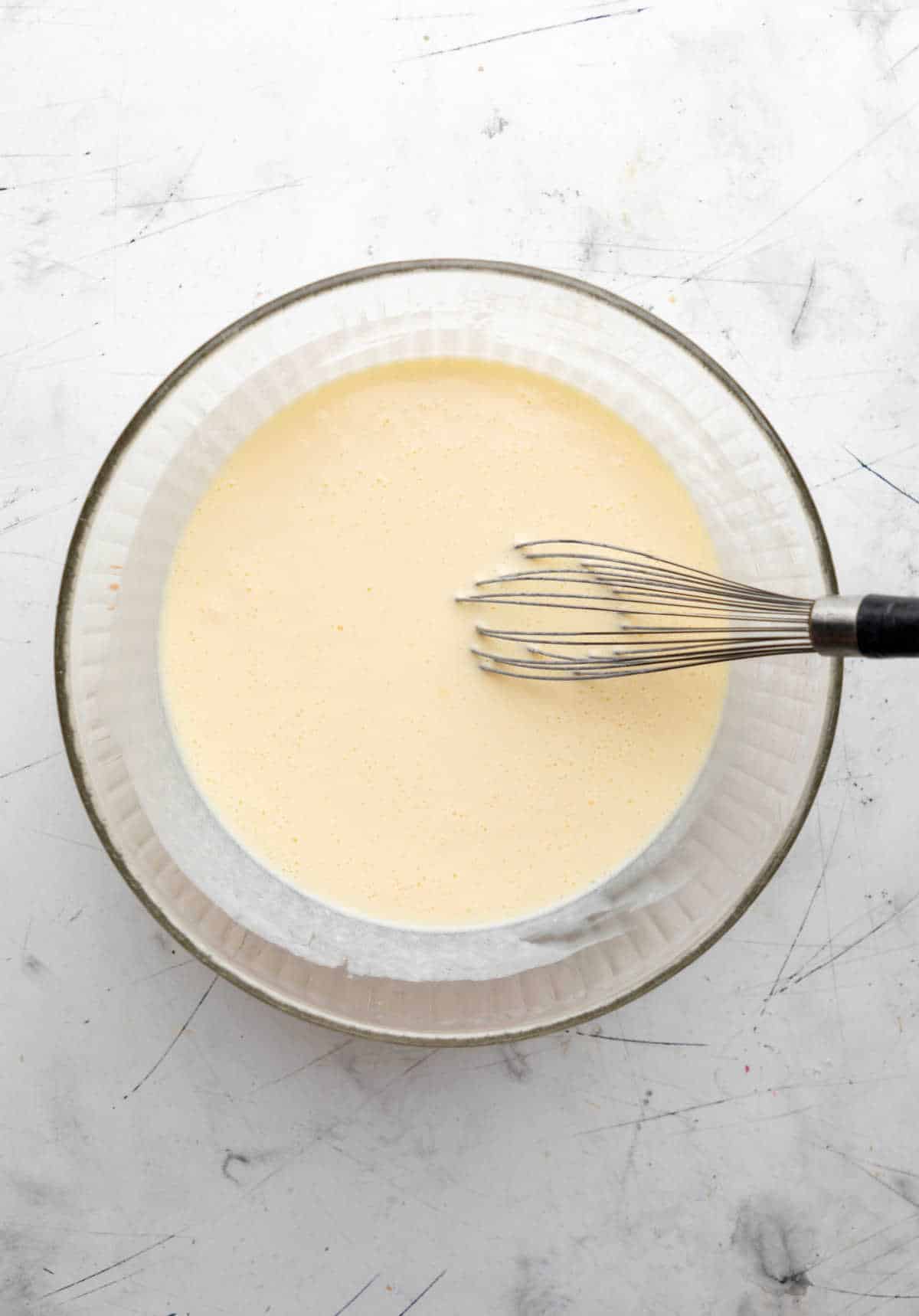 Wet ingredients for buttermilk waffles in a glass mixing bowl. 