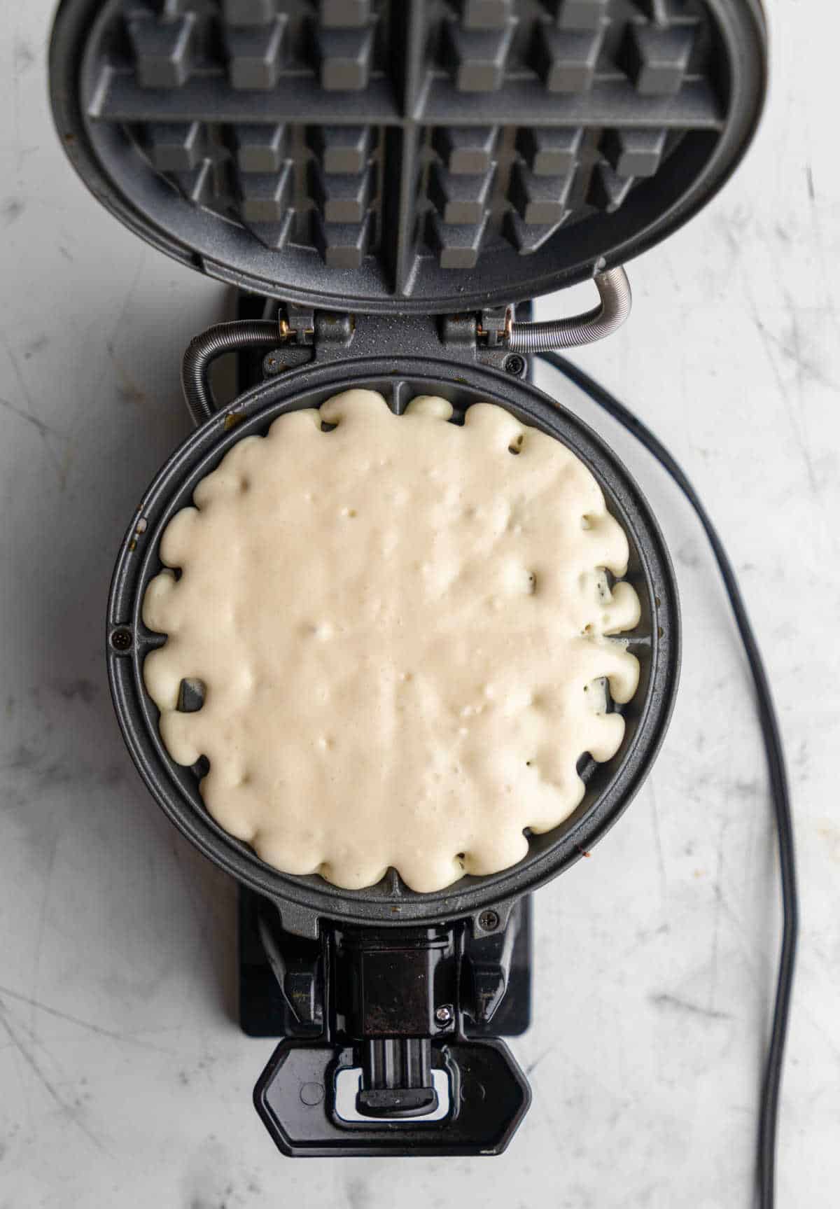 Buttermilk waffle batter in a waffle iron.