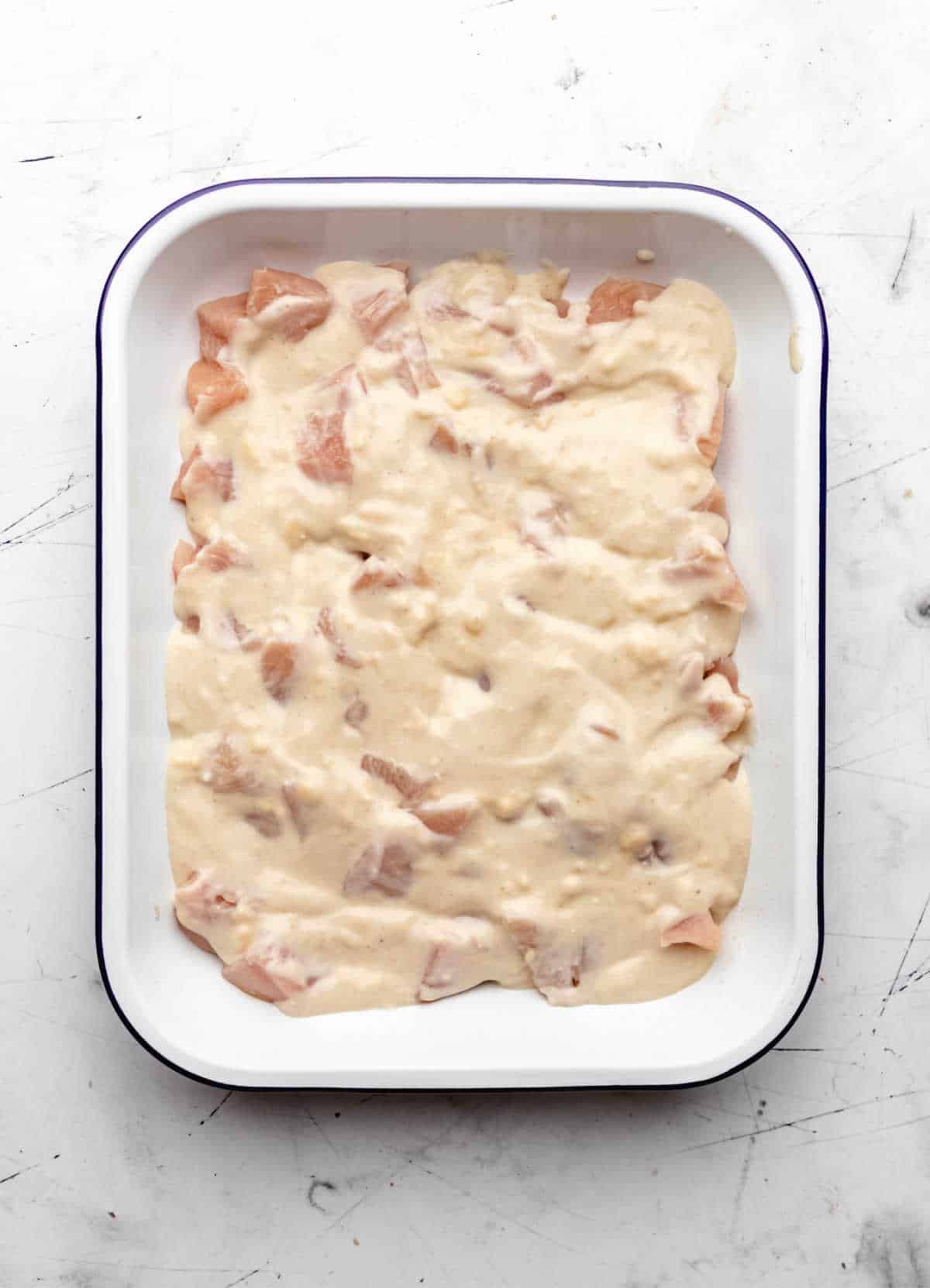 Soup mixture in a layer over chicken pieces.