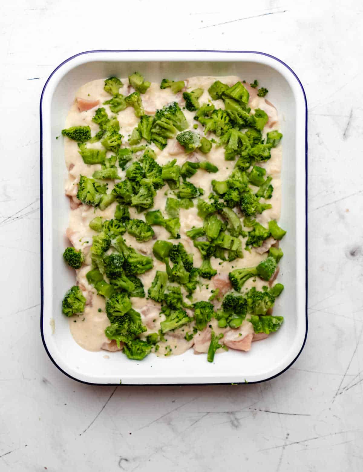 Broccoli pieces over sour cream mixture in a pan.